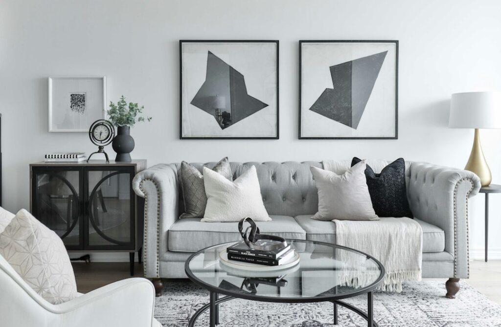 Living room with an upholstered sofa, simple wood tables, textured pillows, and carefully arranged decorative accents.