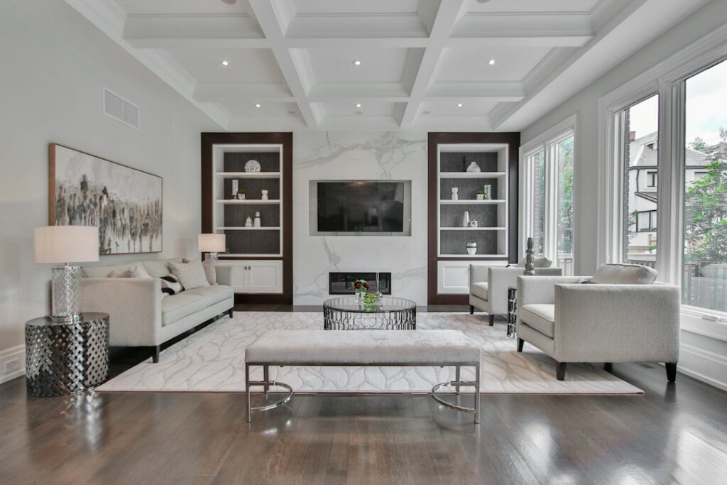 A refined living room combines a streamlined sofa, carved wood table, layered textiles, and warm natural light.