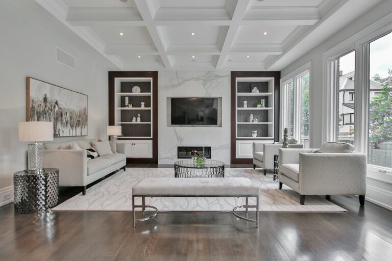 A refined living room combines a streamlined sofa, carved wood table, layered textiles, and warm natural light.