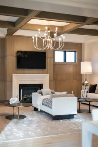 A refined living room with tailored seating, natural wood furniture, layered lighting, and textured fabrics.